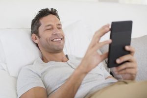 Mann liegt im Bett und schreibt seiner Ex auf dem Handy